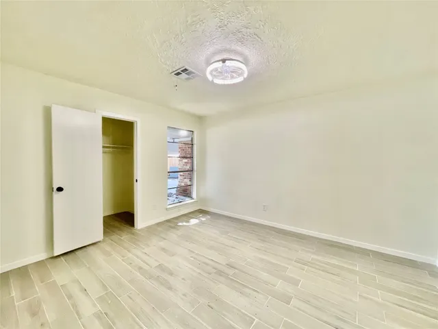 a view of an empty room with closet and a window