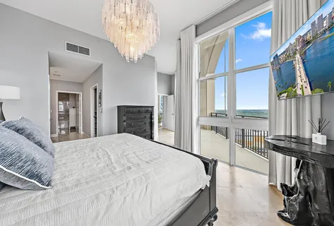 a bedroom with a bed next to a window and a chandelier