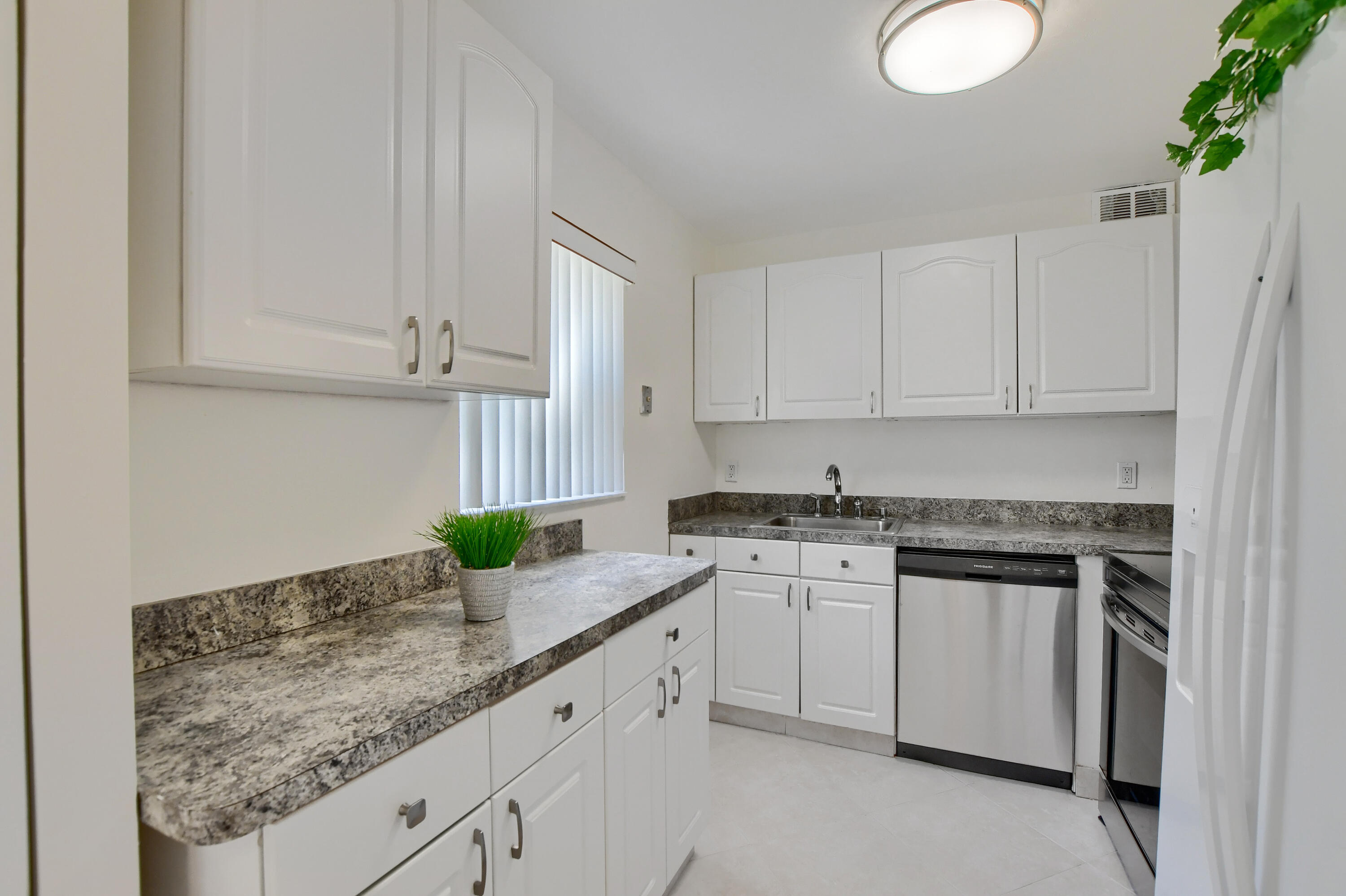 a kitchen with granite countertop a sink stainless steel appliances and white cabinets
