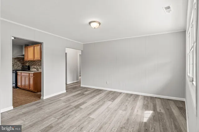 a view of an empty room with kitchen and a window