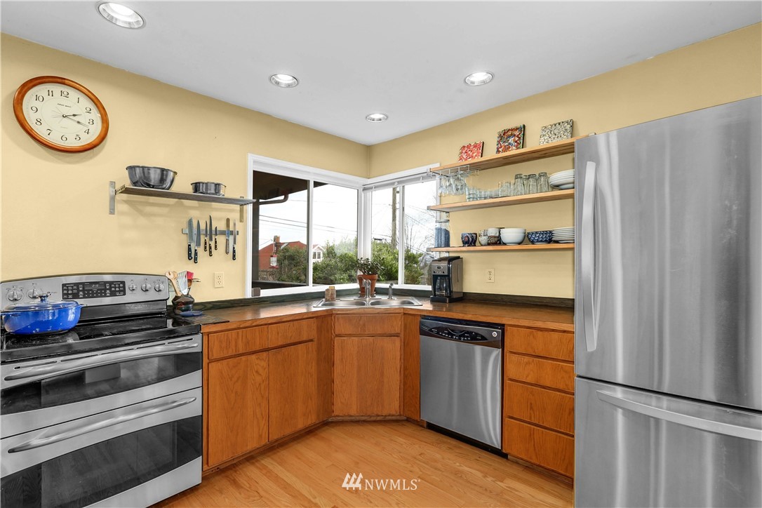 2418 East Roy Street Seattle, WA 98112 - Photo 14 of 32 a kitchen with stainless steel appliances granite countertop a refrigerator and a stove top oven