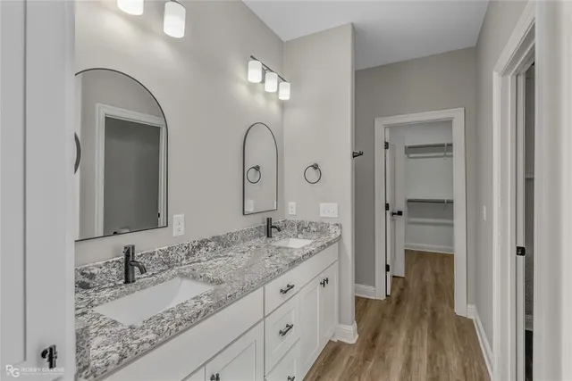 a bathroom with a granite countertop double vanity sink and a mirror