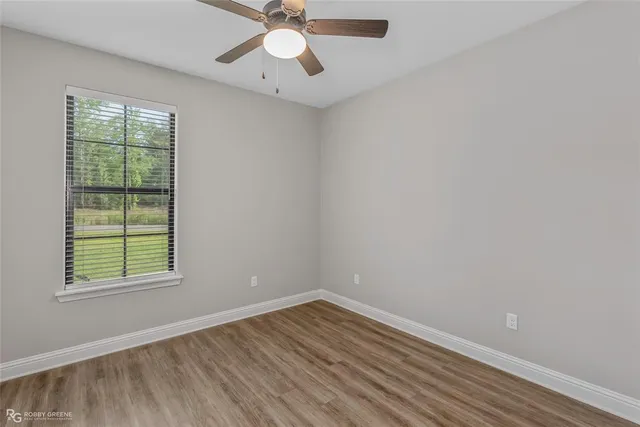 an empty room with wooden floor chandelier fan and windows