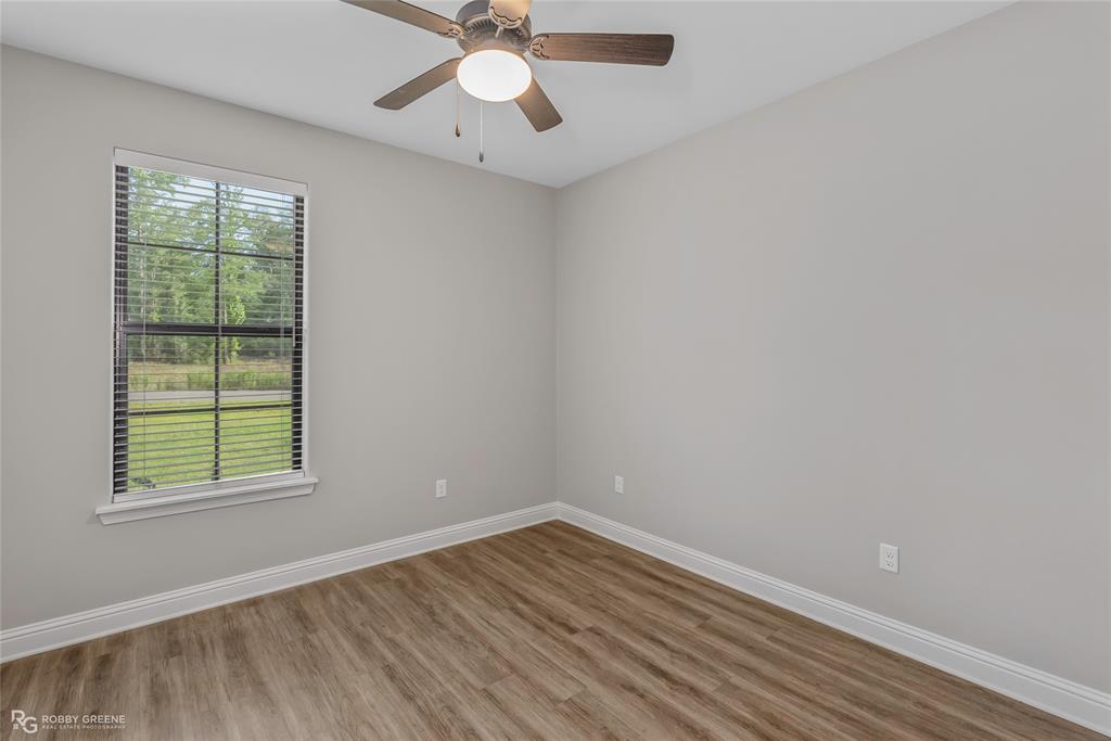 1013 VOSS Road Stonewall, LA 71078 - Photo 25 of 32 an empty room with wooden floor chandelier fan and windows