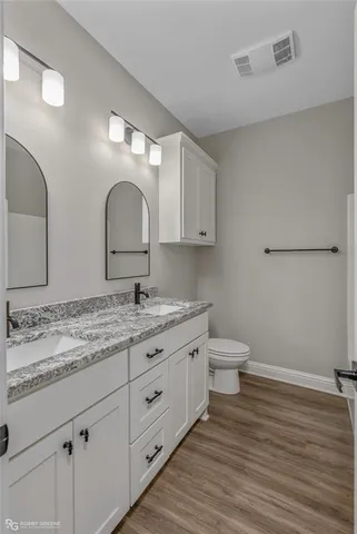 a bathroom with a granite countertop toilet sink and mirror