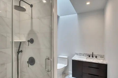 a bathroom with a granite countertop sink a toilet and shower
