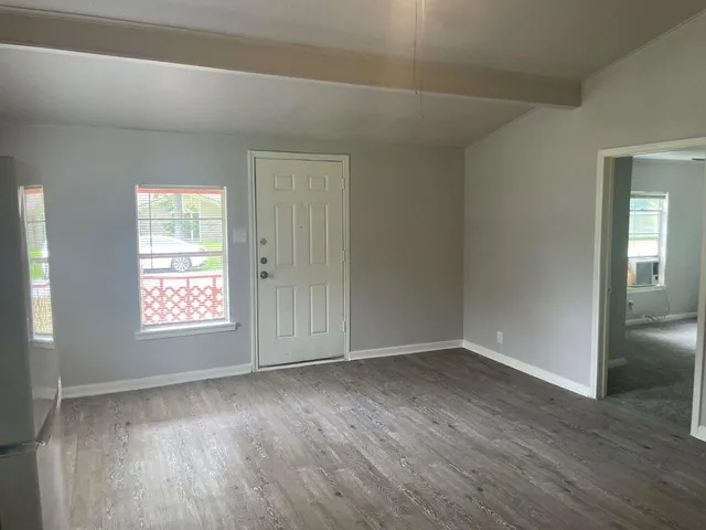 an empty room with wooden floor and window