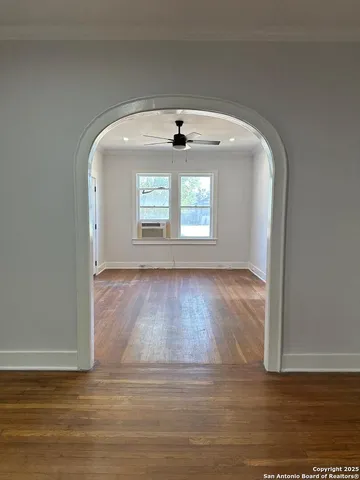 a view of an empty room with wooden floor and a window
