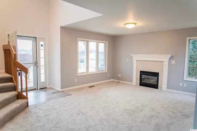 a view of an empty room with a fireplace and a window