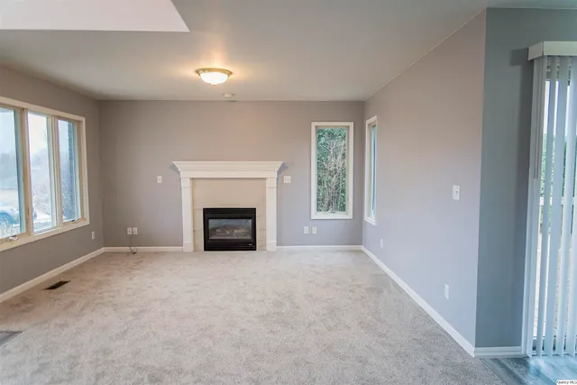 an empty room with windows and fireplace