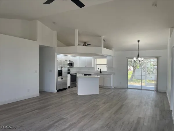 a kitchen with stainless steel appliances wooden floor and chandelier