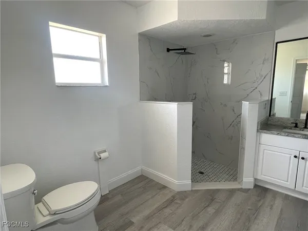 a bathroom with a granite countertop toilet a sink a mirror and vanity