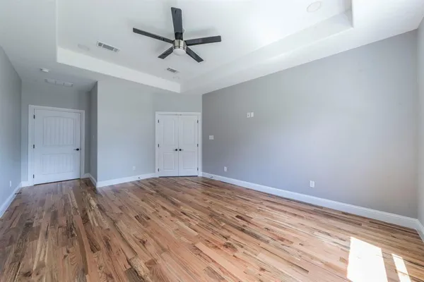 a view of empty room with wooden floor and fan