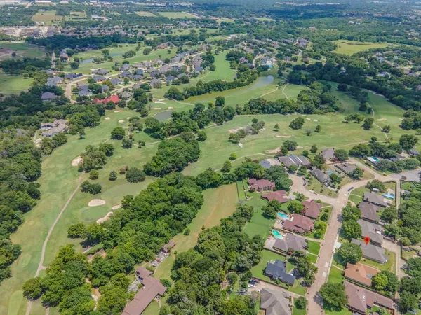 an aerial view of residential houses with outdoor space and trees