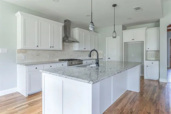 a kitchen with stainless steel appliances granite countertop a sink a refrigerator and white cabinets