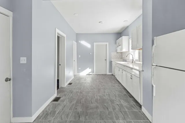 a view of a kitchen with refrigerator and white cabinets
