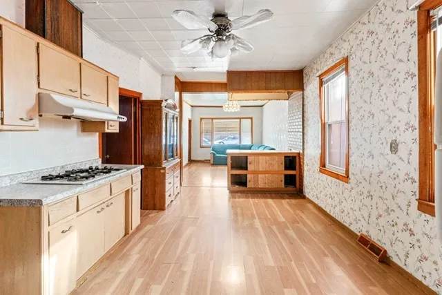 a kitchen with stainless steel appliances granite countertop a stove a refrigerator a sink dishwasher and a dining table with wooden floor