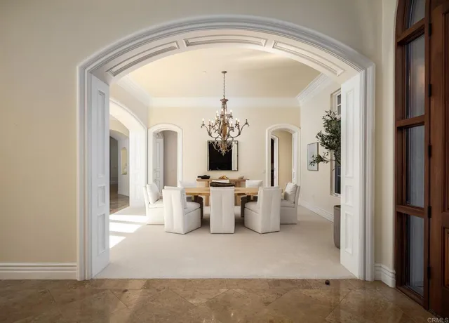 a view of a hallway with a dining table and chandelier