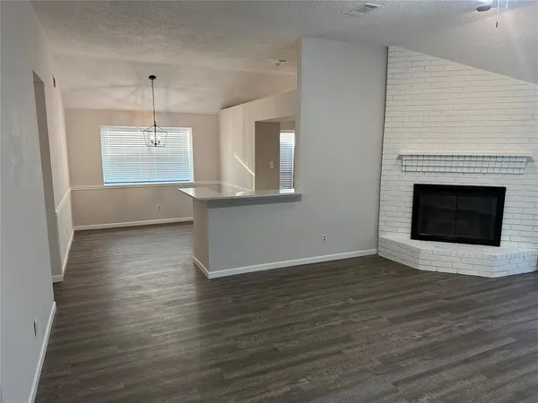 an empty room with wooden floor a ceiling fan a fireplace and windows
