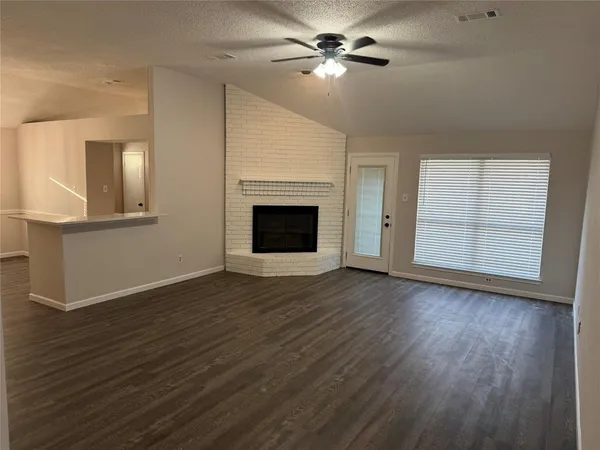 an empty room with wooden floor chandelier fan and windows
