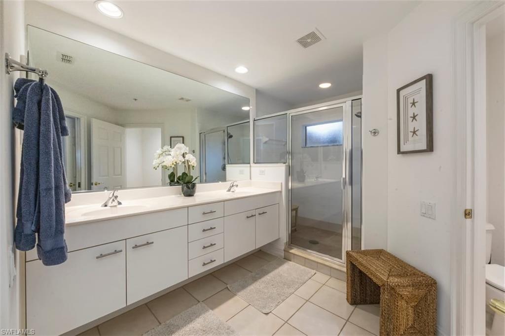 866 Carrick Bend Circle, Unit 201 Naples, FL 34110 - Photo 19 of 35 a bathroom with a double vanity sink a toilet a mirror a shower and vanity