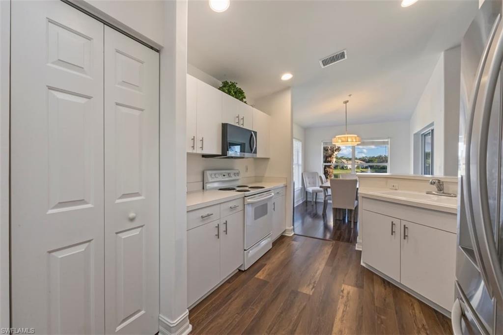 866 Carrick Bend Circle, Unit 201 Naples, FL 34110 - Photo 10 of 35 a kitchen with white cabinets and stainless steel appliances