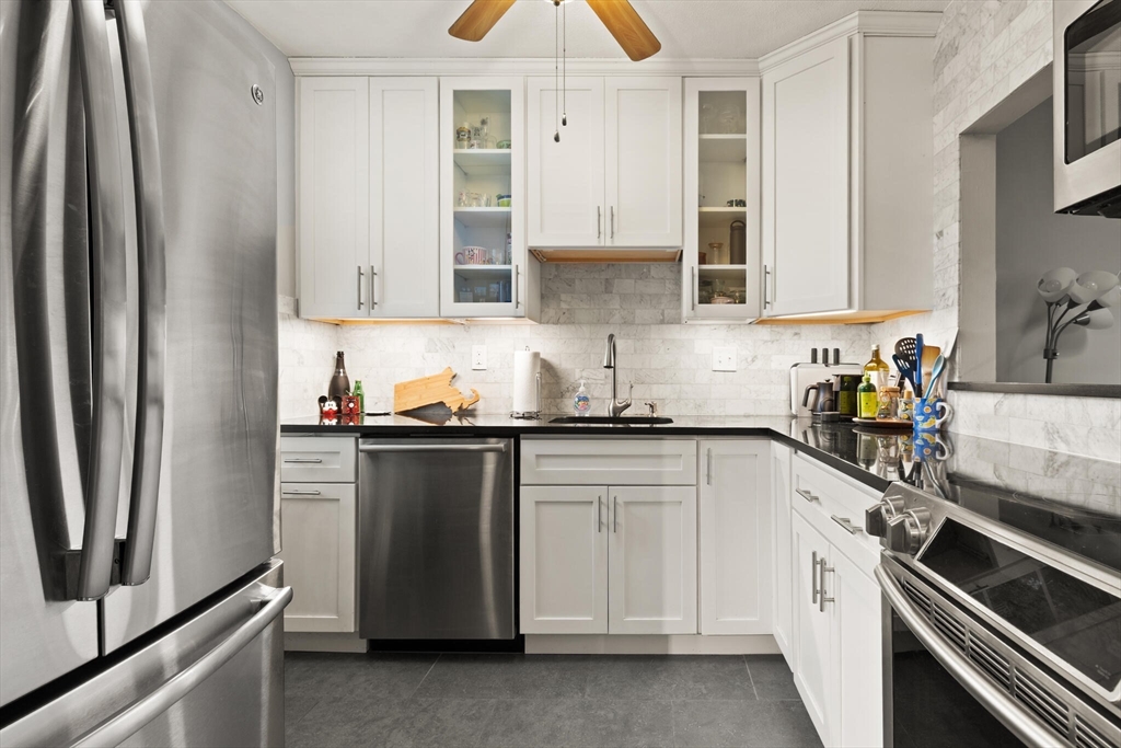 a kitchen with granite countertop white cabinets and stainless steel appliances