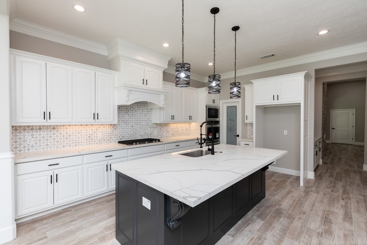 7705 Water Edge Beaumont, TX 77707 - Photo 6 of 39 a kitchen with kitchen island a sink dishwasher stove and white cabinets with wooden floor
