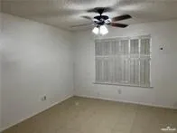 an empty room with a chandelier fan and windows