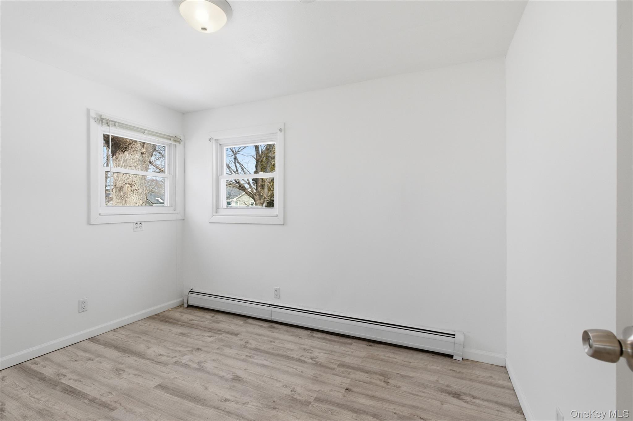 717 Doane Avenue Bellport, NY 11713 - Photo 15 of 22 Unfurnished room with a baseboard heating unit and light wood-style floors