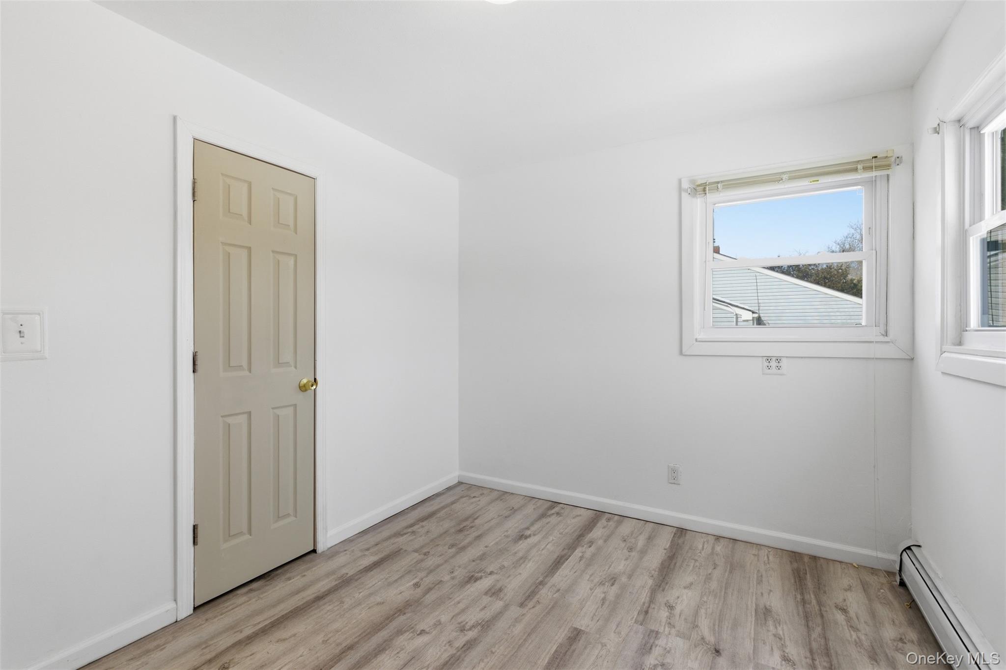 717 Doane Avenue Bellport, NY 11713 - Photo 16 of 22 Spare room featuring baseboard heating and light wood-style floors