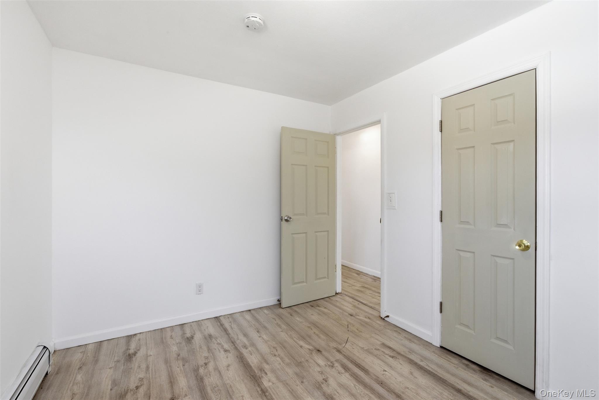 717 Doane Avenue Bellport, NY 11713 - Photo 17 of 22 Unfurnished bedroom with baseboard heating and light wood finished floors