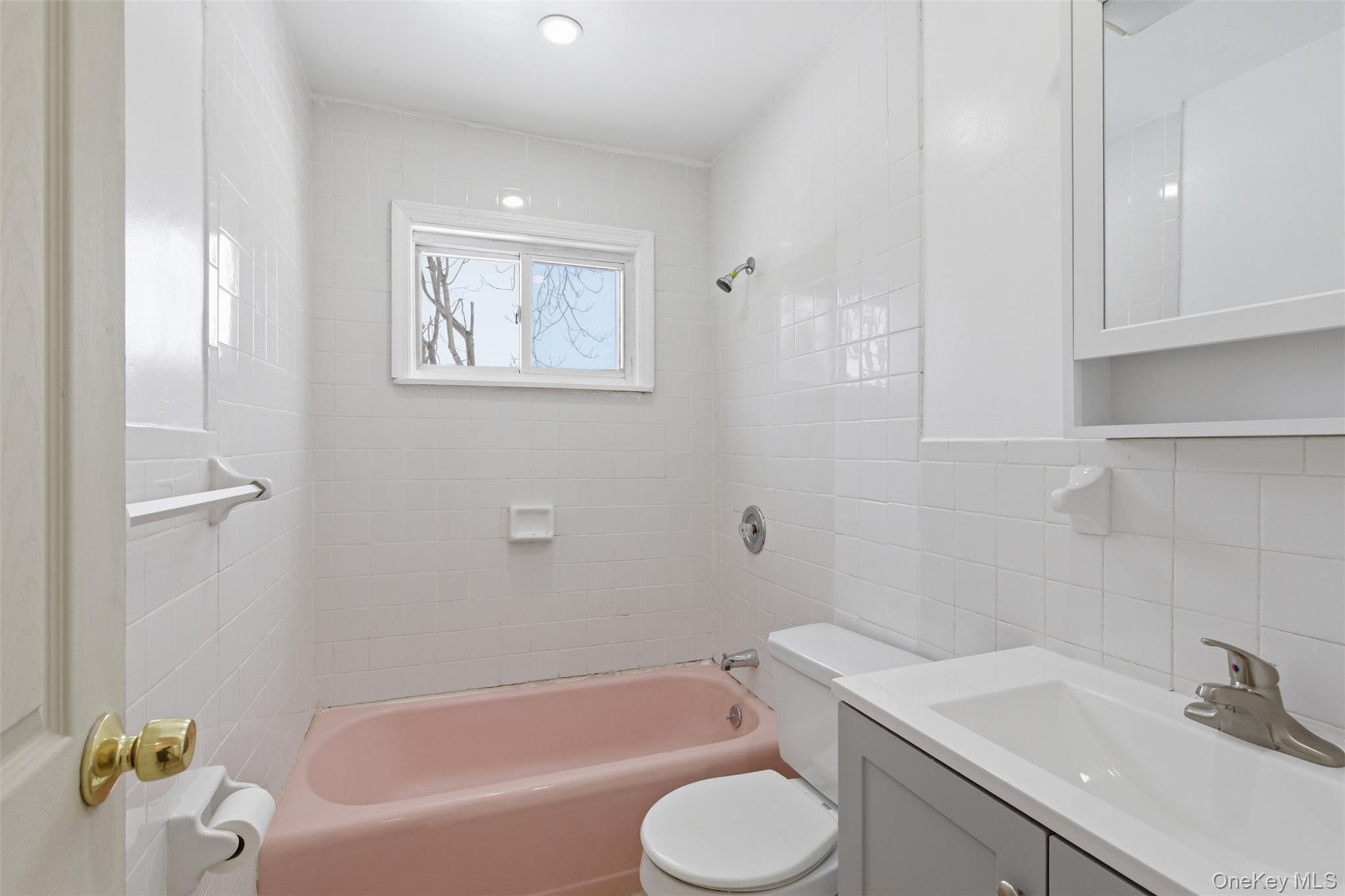 717 Doane Avenue Bellport, NY 11713 - Photo 18 of 22 Full bath featuring vanity, tile walls, and bathing tub / shower combination