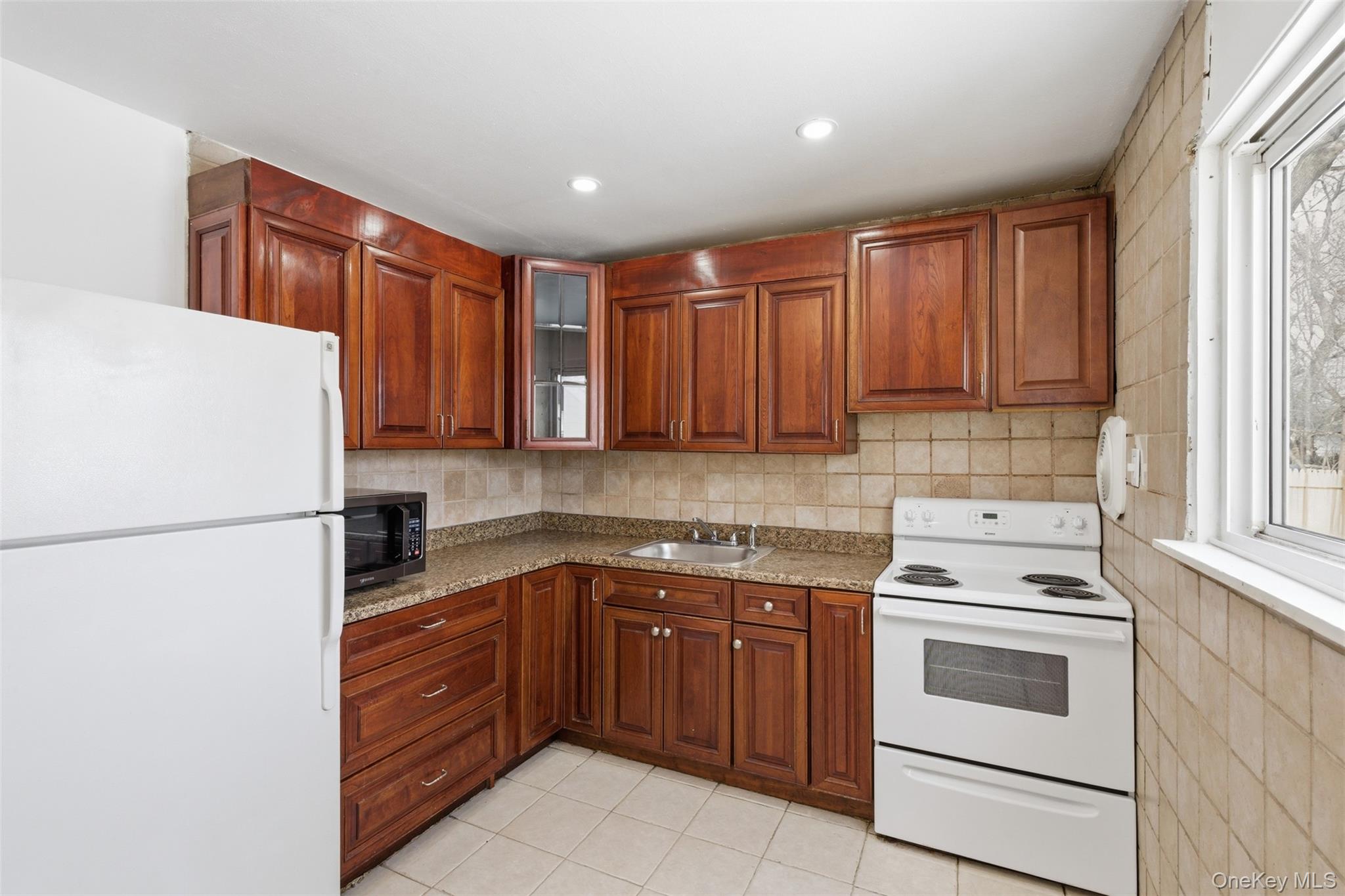 717 Doane Avenue Bellport, NY 11713 - Photo 4 of 22 Kitchen featuring white appliances, glass fronted cabinets, light tile patterned floors, light stone countertops, and wood finish cabinetry