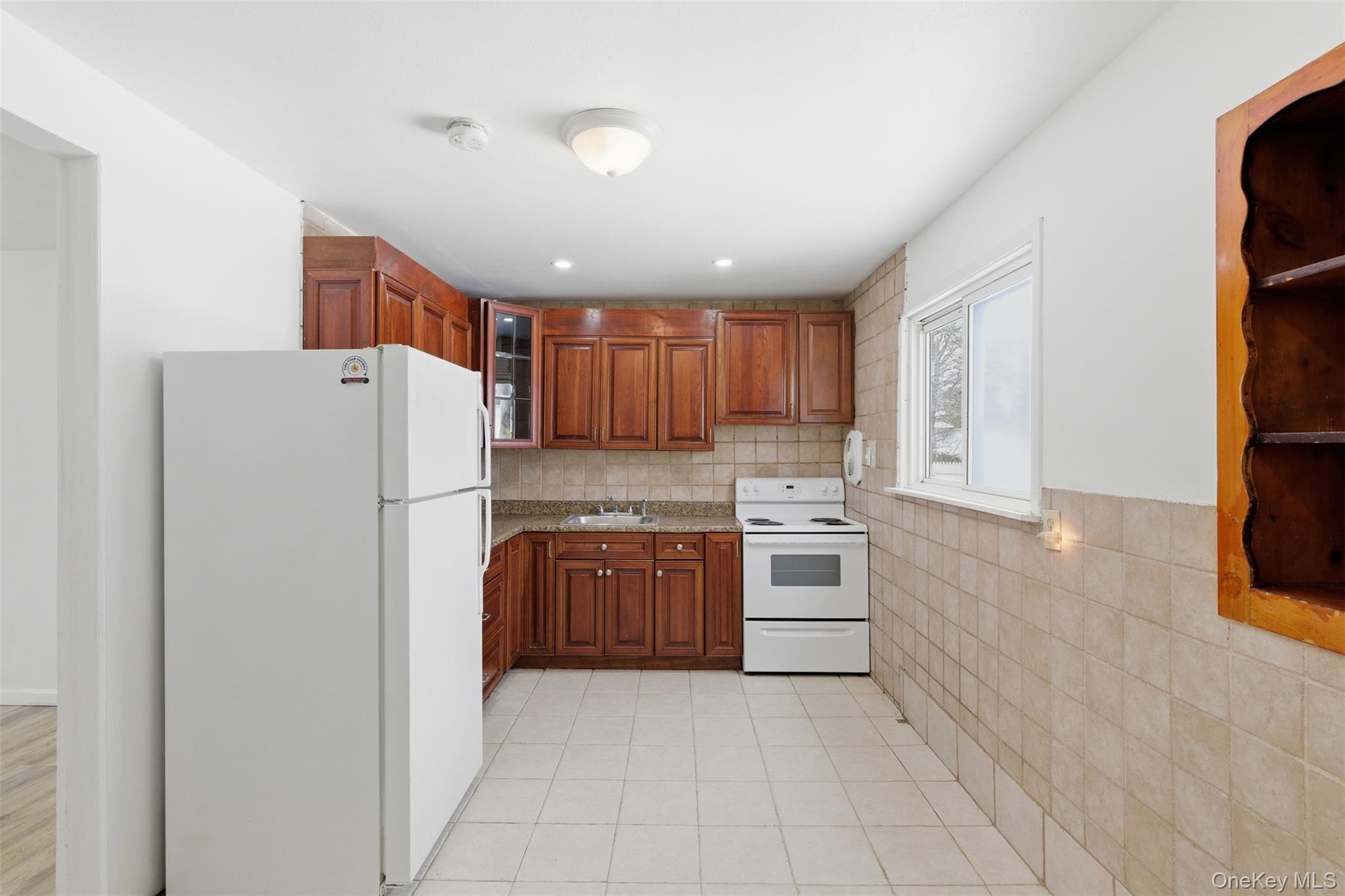 717 Doane Avenue Bellport, NY 11713 - Photo 5 of 22 Kitchen featuring white appliances, wood finish cabinets, glass insert cabinets, light tile patterned floors, and recessed lighting