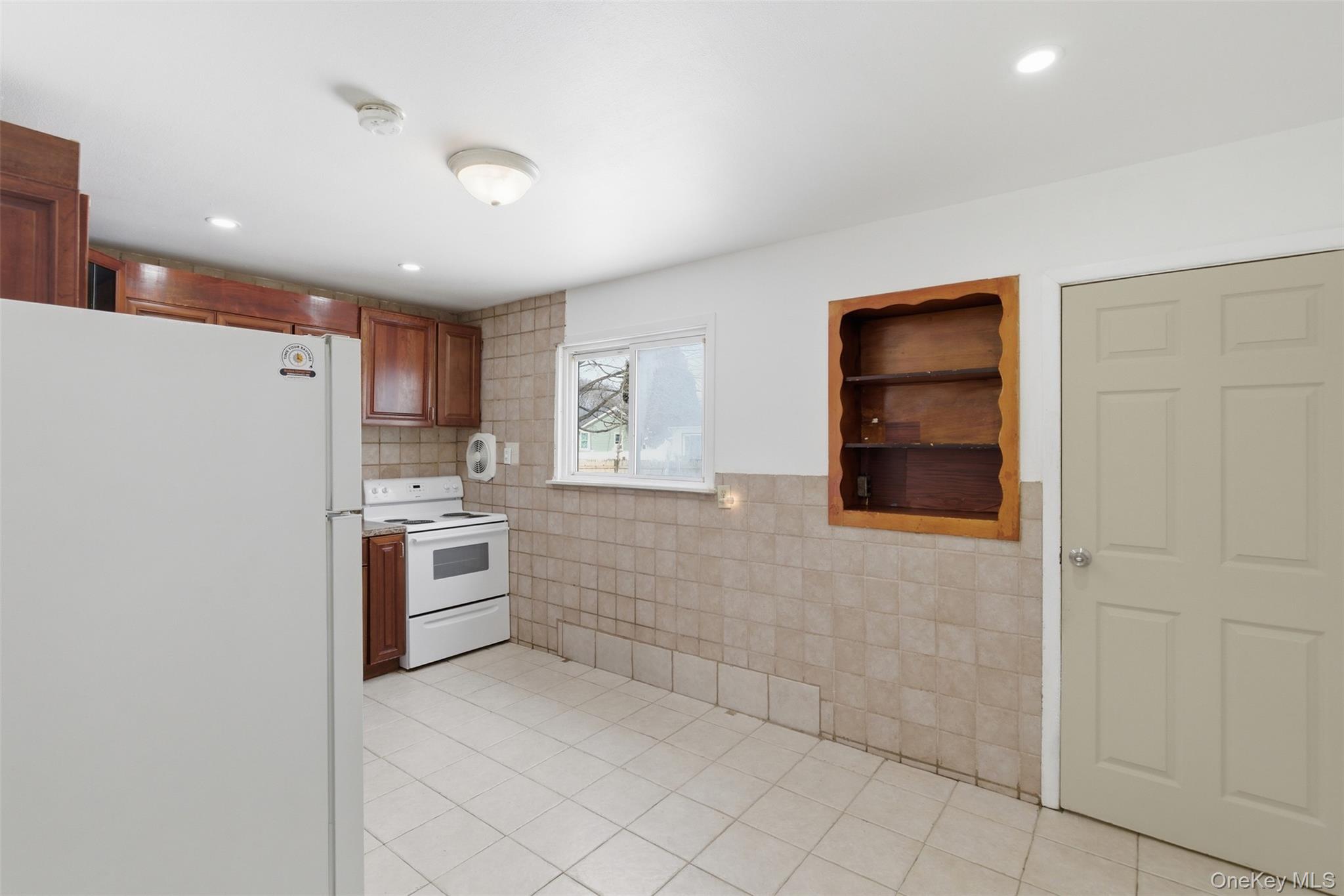 717 Doane Avenue Bellport, NY 11713 - Photo 6 of 22 Kitchen with white appliances, tile walls, light tile patterned floors, wood finish cabinets, and light countertops