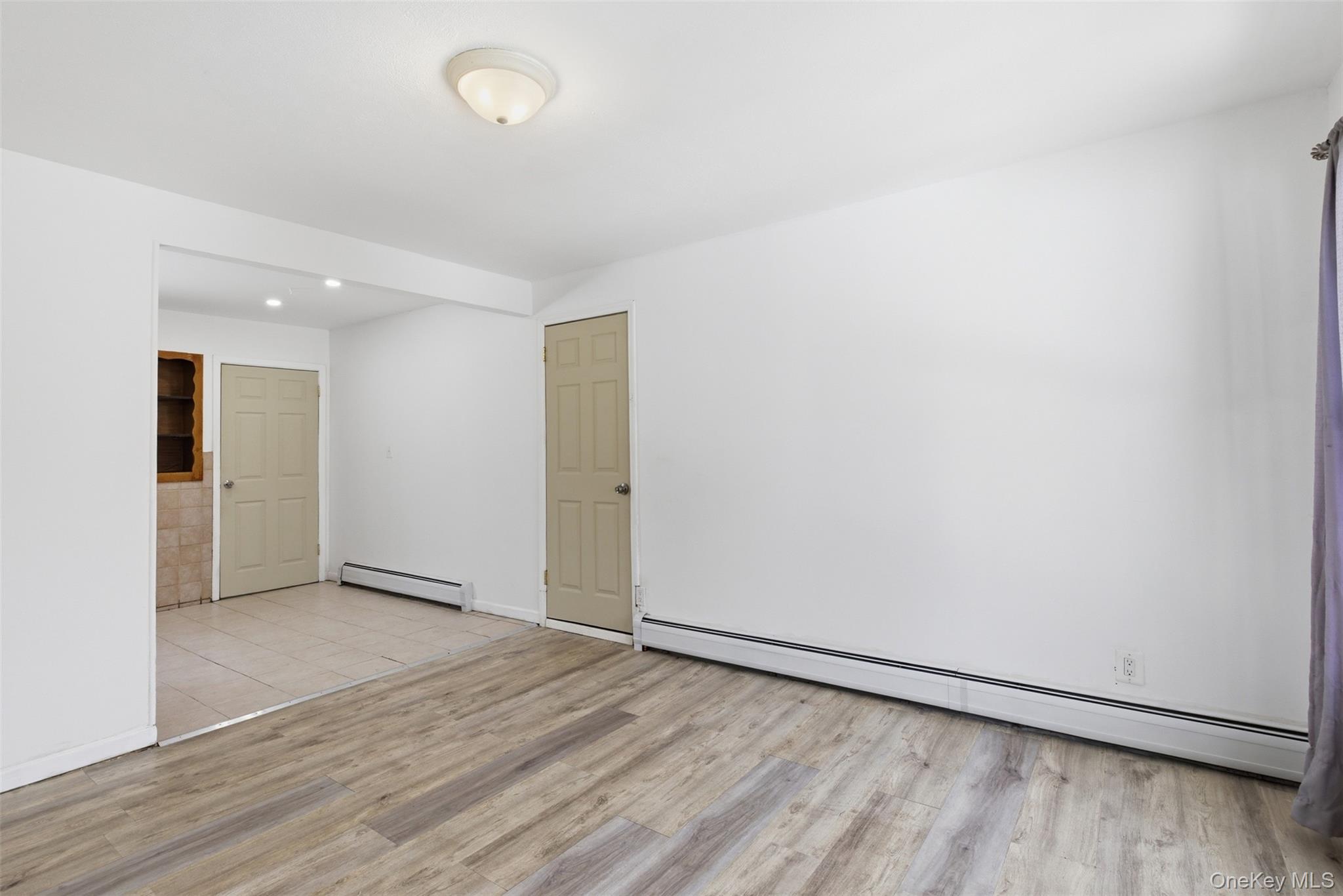 717 Doane Avenue Bellport, NY 11713 - Photo 10 of 22 Spare room with a baseboard heating unit and light wood-style flooring