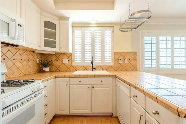 a kitchen with granite countertop a sink and white cabinets with wooden floor