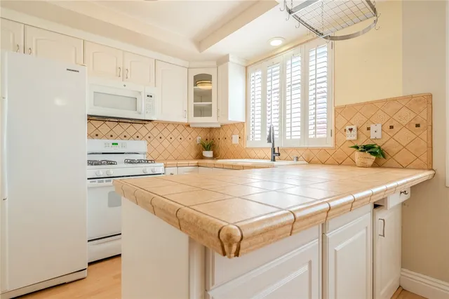 a kitchen with a sink a stove and white cabinets