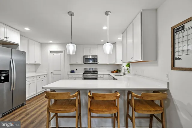 a kitchen with stainless steel appliances granite countertop a sink a stove a refrigerator and chairs