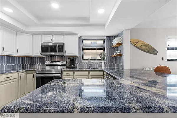 a kitchen with kitchen island granite countertop a sink and a stove top oven
