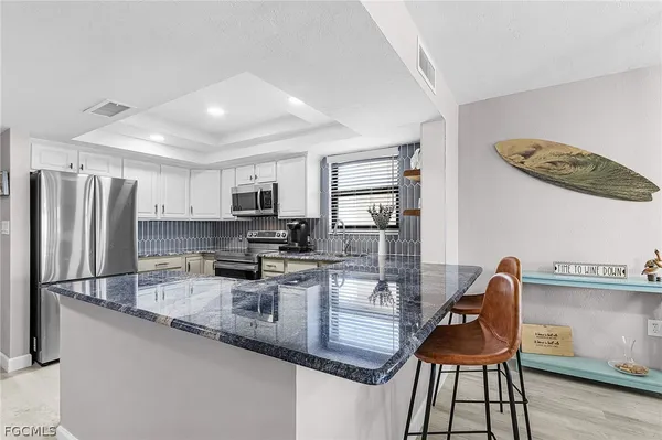 a kitchen with stainless steel appliances granite countertop a stove top oven a sink a dining table and chairs