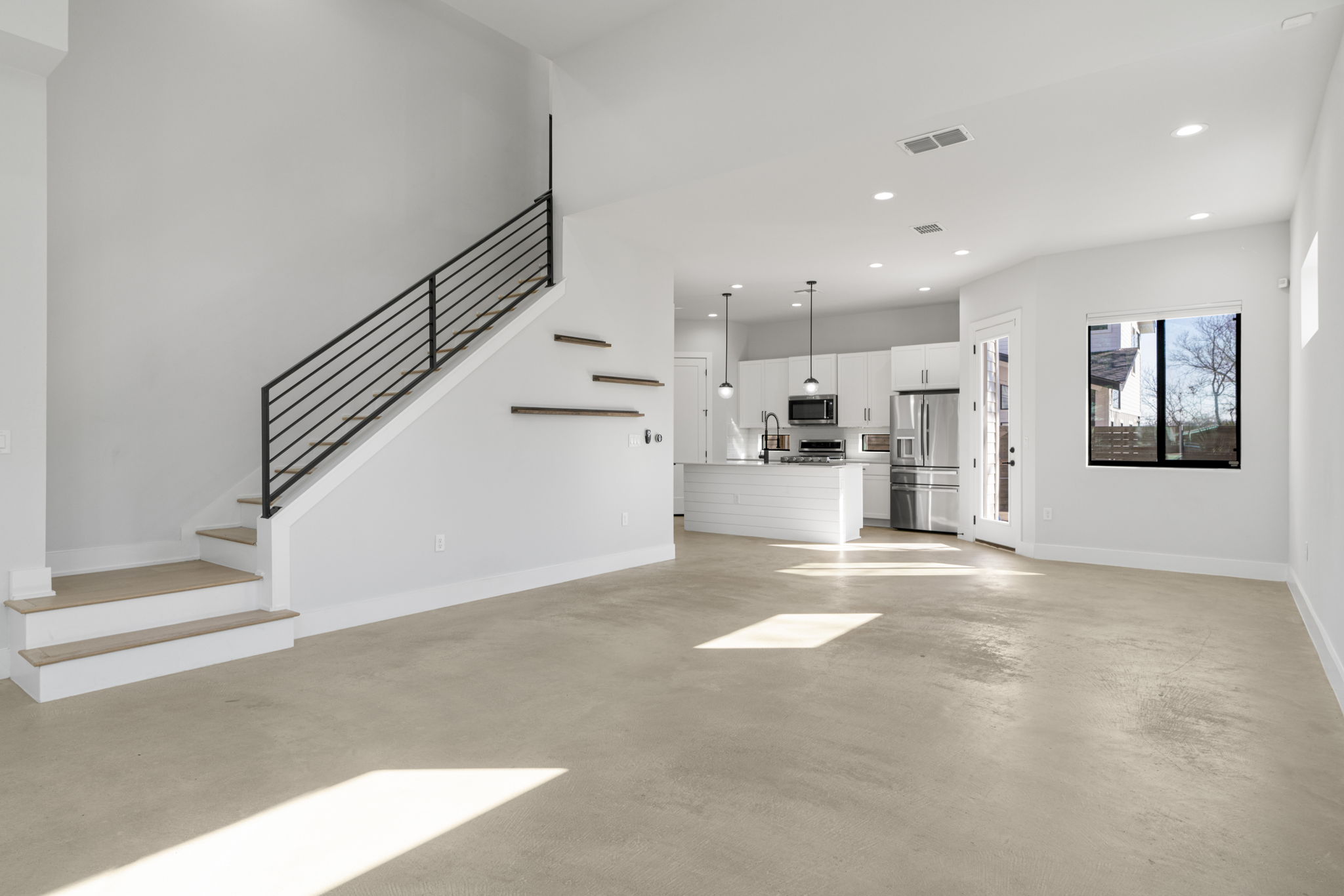 1405 Perez Street, Unit 1 Austin, TX 78721 - Photo 3 of 30 Spacious open-concept design connects the living room to the kitchen, featuring recessed lighting and a sleek staircase with modern railing detail.