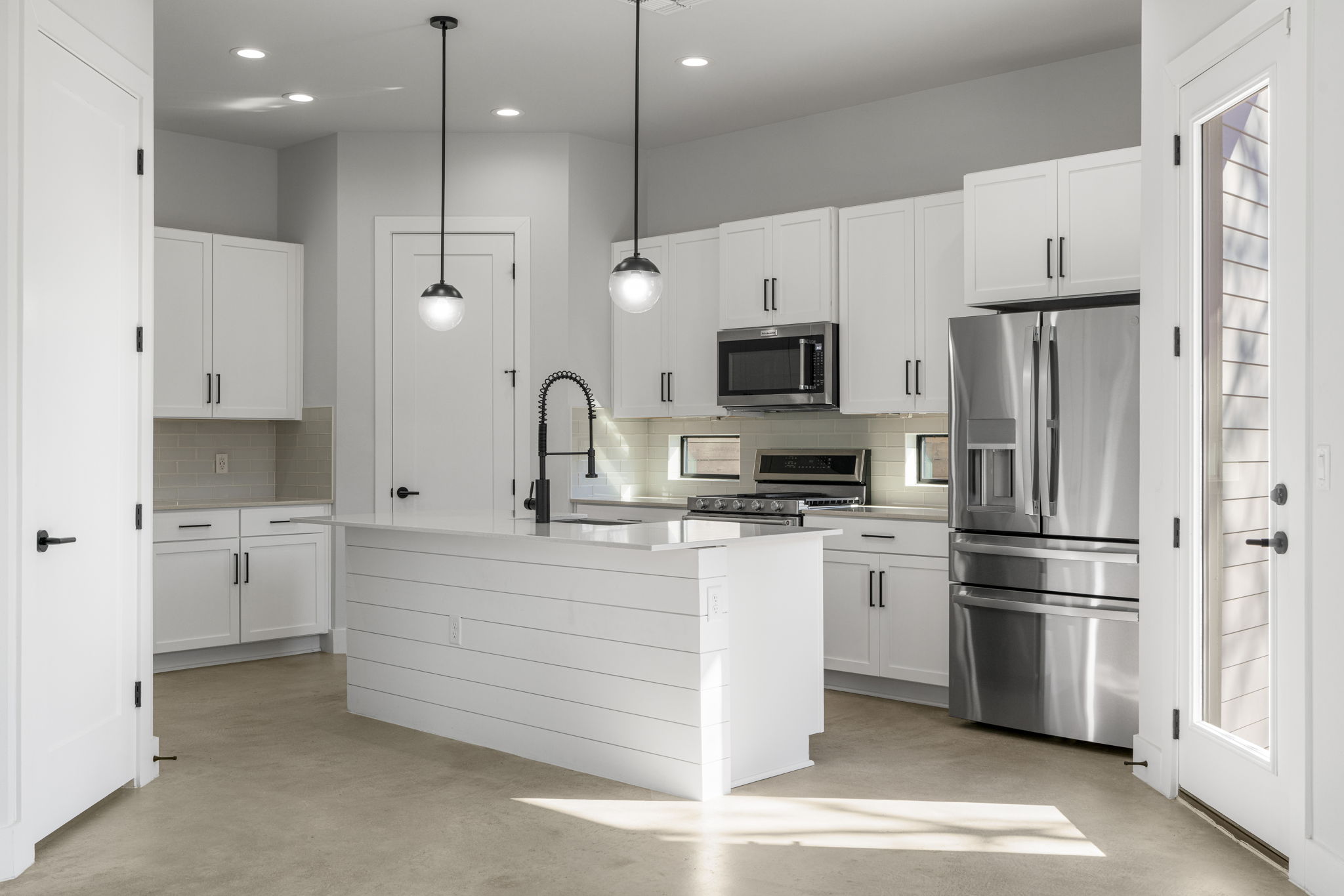 1405 Perez Street, Unit 1 Austin, TX 78721 - Photo 4 of 30 Modern kitchen with white shaker cabinetry, quartz countertops, stainless steel appliances, and a center island with statement pendant lighting. Functional layout offers ample prep and storage space.