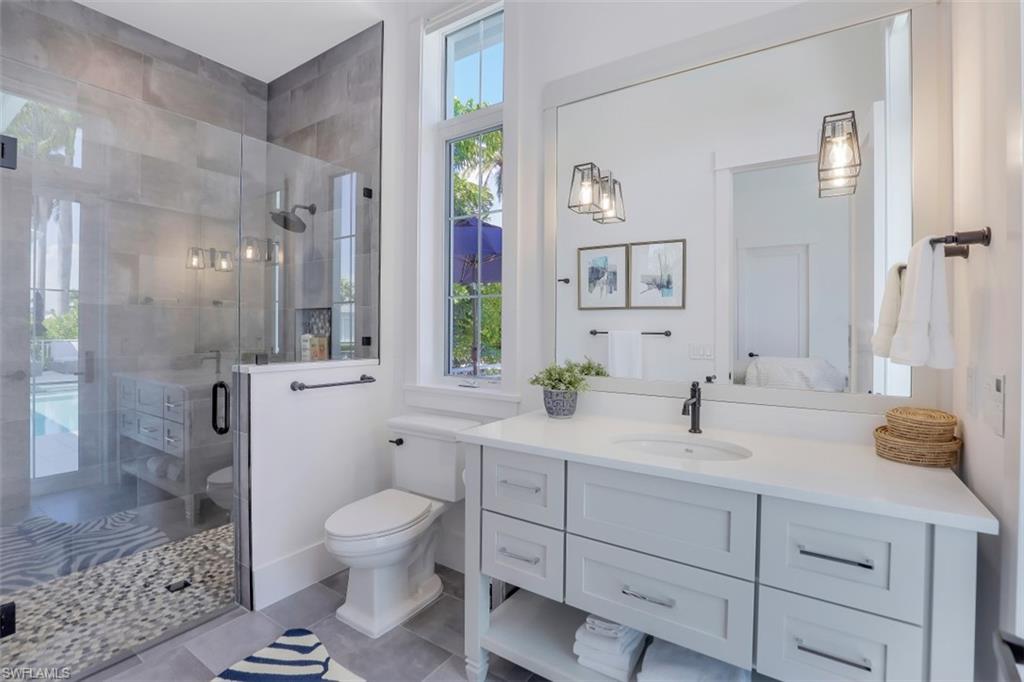 2130 Tarpon Road Naples, FL 34102 - Photo 25 of 35 a spacious bathroom with a granite countertop sink toilet a large mirror a shower and a mirror