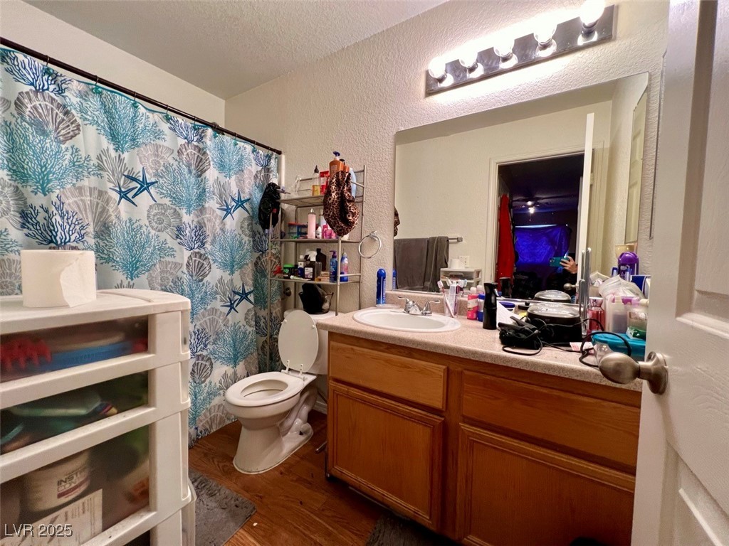4730 East Craig Road, Unit 2071 Las Vegas, NV 89115 - Photo 12 of 23 Full bath featuring a textured wall, dark wood-style floors, a shower with curtain, vanity, and a textured ceiling