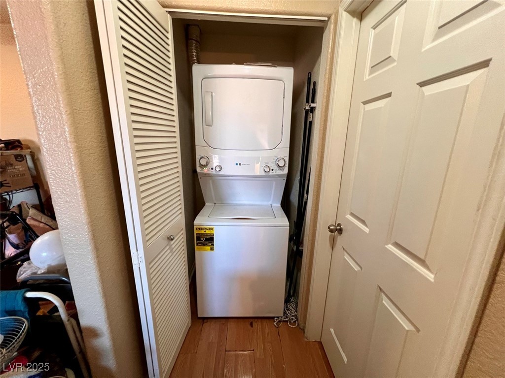 4730 East Craig Road, Unit 2071 Las Vegas, NV 89115 - Photo 13 of 23 Laundry room featuring light wood-style flooring, stacked washer and clothes dryer, and a textured wall
