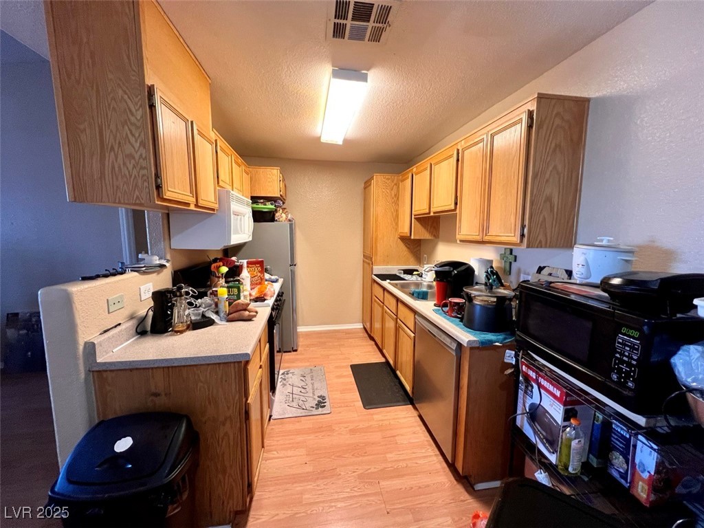 4730 East Craig Road, Unit 2071 Las Vegas, NV 89115 - Photo 5 of 23 Kitchen featuring stainless steel appliances, a textured ceiling, light wood finished floors, a textured wall, and light brown cabinetry