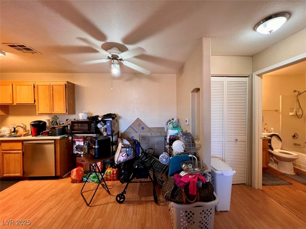4730 East Craig Road, Unit 2071 Las Vegas, NV 89115 - Photo 7 of 23 Kitchen featuring light wood-type flooring, light countertops, a textured ceiling, a textured wall, and stainless steel dishwasher