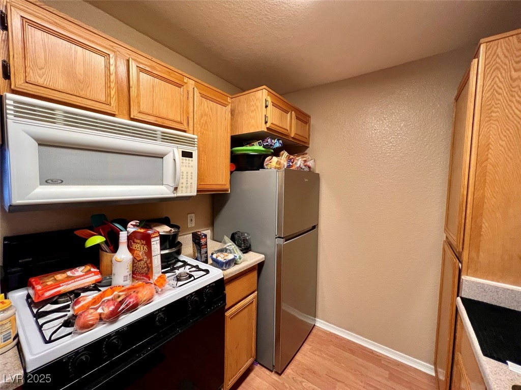 4730 East Craig Road, Unit 2071 Las Vegas, NV 89115 - Photo 8 of 23 Kitchen featuring black gas range, white microwave, light wood finished floors, a textured wall, and light countertops